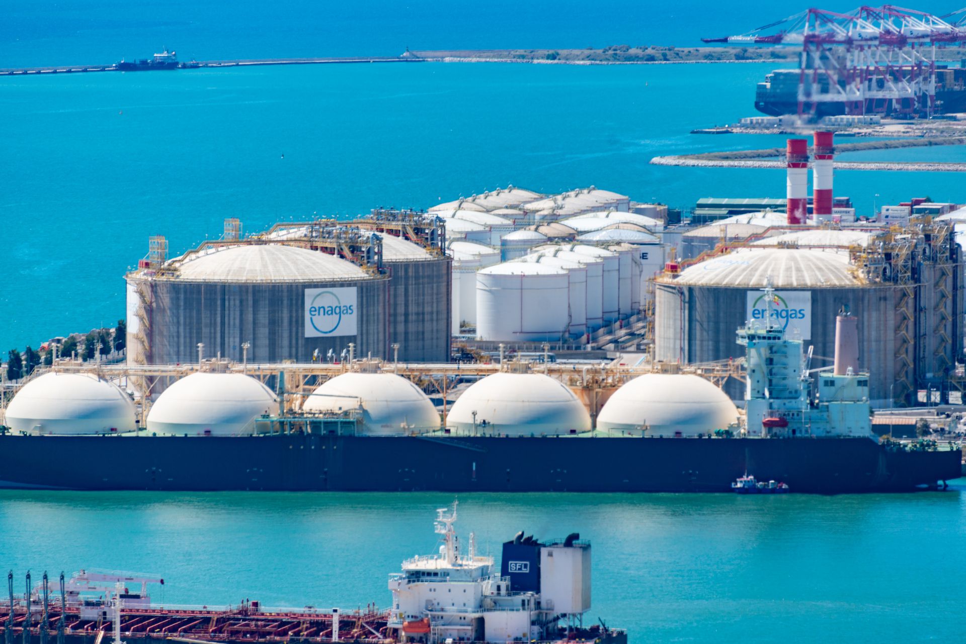 Aerial view of an LNG terminal with storage tanks and a tanker ship at berth